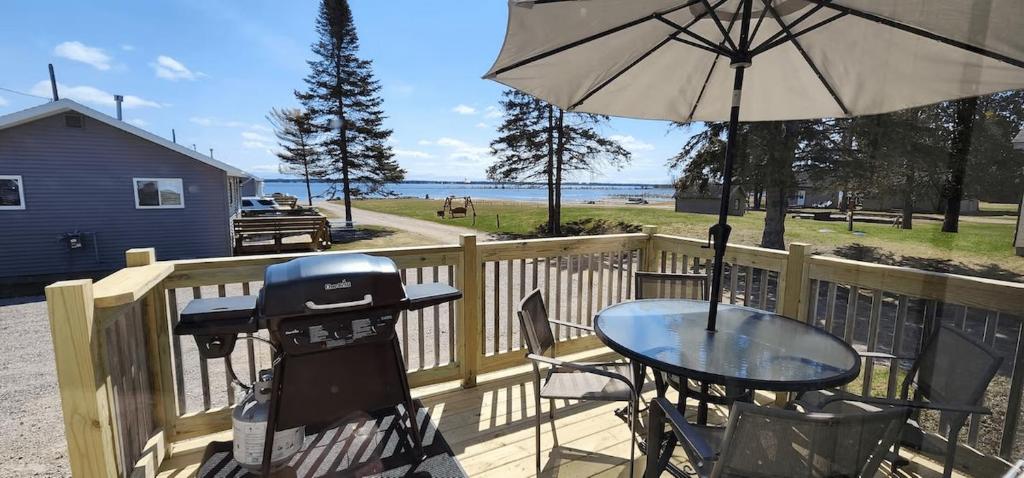 a grill and a table with an umbrella on a deck at #7 Kipling Cottages Last Resort on Lake Michigan in Gladstone