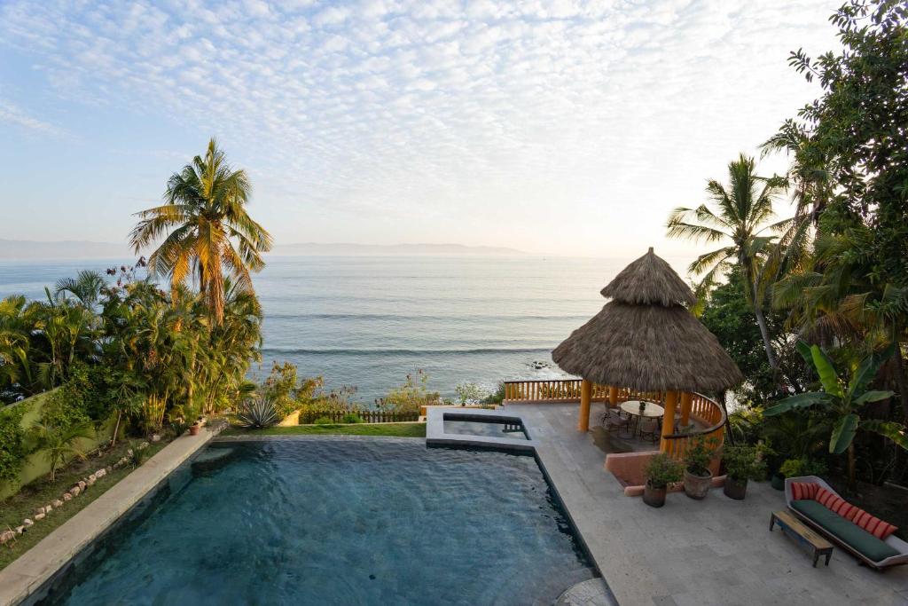 a swimming pool with a gazebo and the ocean at Casa Tara Villa Oceanfront Oasis Private Beach in Cruz de Huanacaxtle
