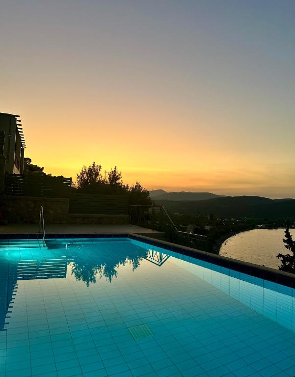 a swimming pool with a sunset in the background at Villa Korina in Nea Epidavros