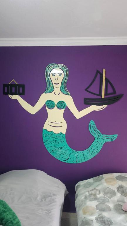 a mural of a mermaid with a ship on a purple wall at Mermaid house in Drama