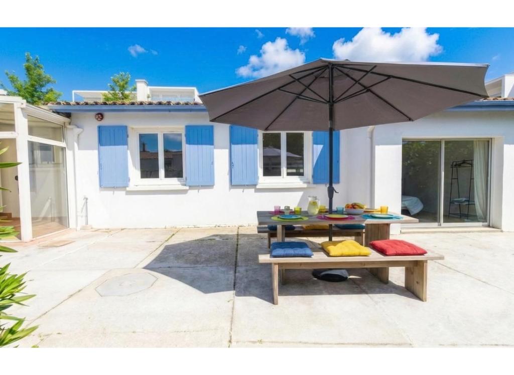 a table with an umbrella in front of a house at Maison plain pied hyper centre avec véranda 5 min à pied plage Royan 3 chambres in Royan