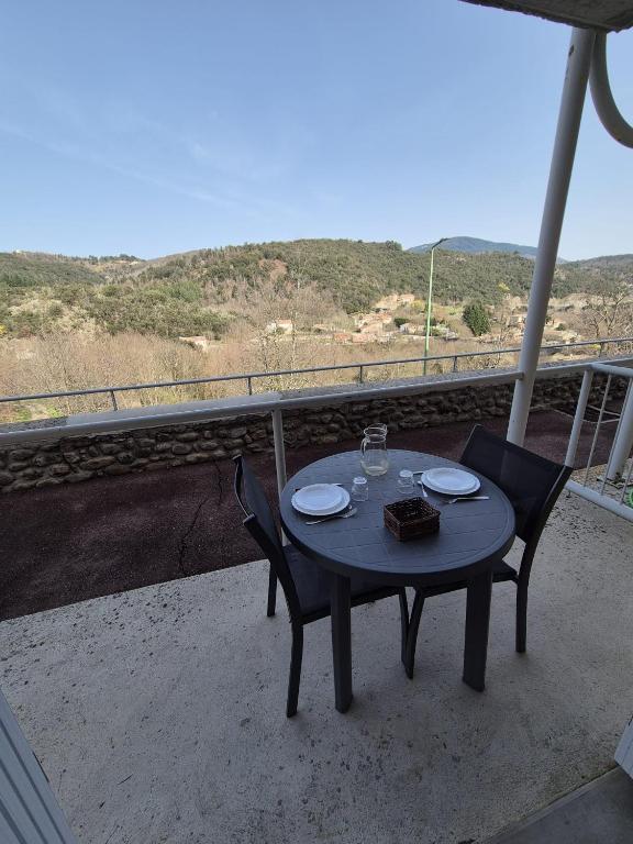 a table and chairs on a balcony with a view at Gîte La Vallée RDC Neyrac-les-Bains in Meyras