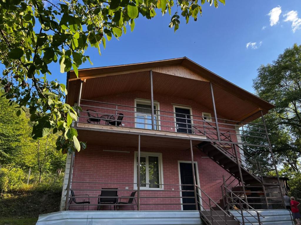 a red brick house with chairs on the balcony at Rachnari Guest House in Gari