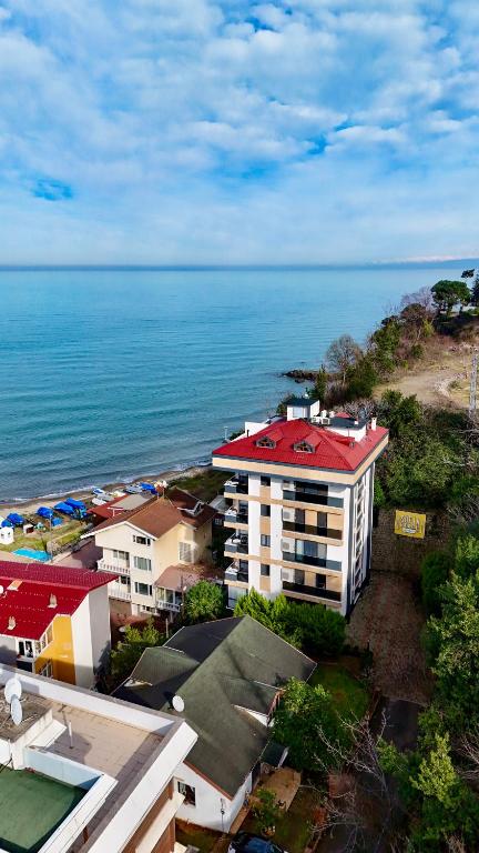 a building with a red roof next to the ocean at Sofia Beach Residence in Trabzon