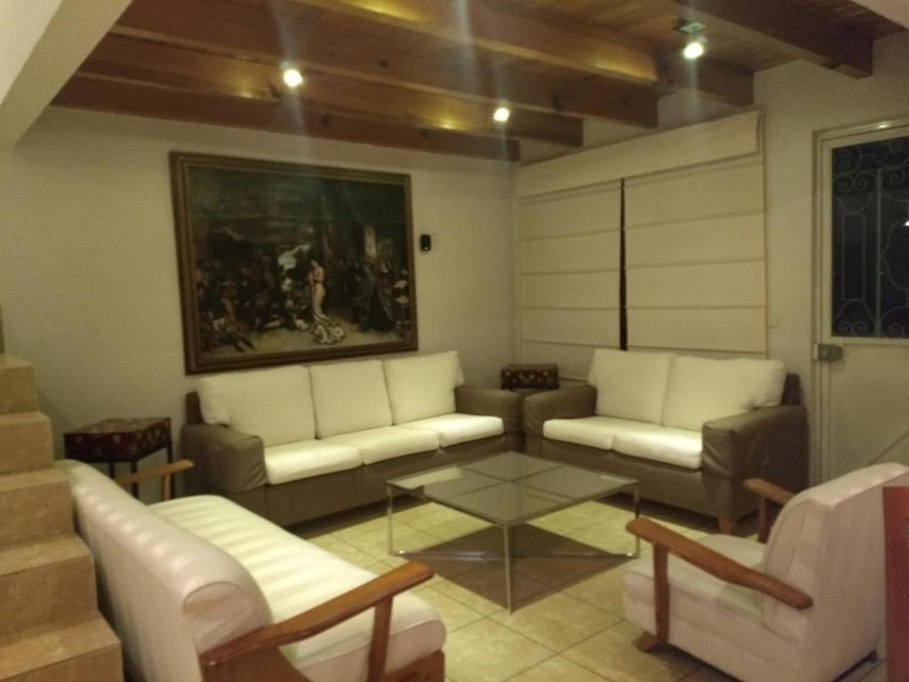 a living room with couches and a table and a painting at Casa en Xochimilco in Mexico City