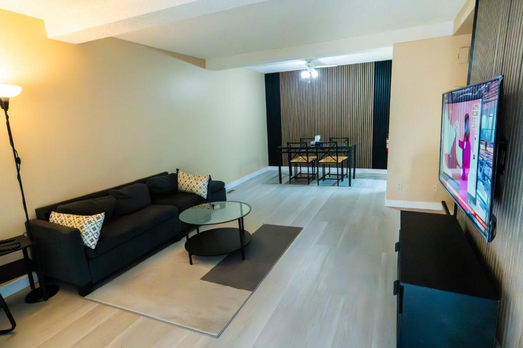 a living room with a couch and a flat screen tv at Charming 2-Bedroom House in Central Calgary in Calgary