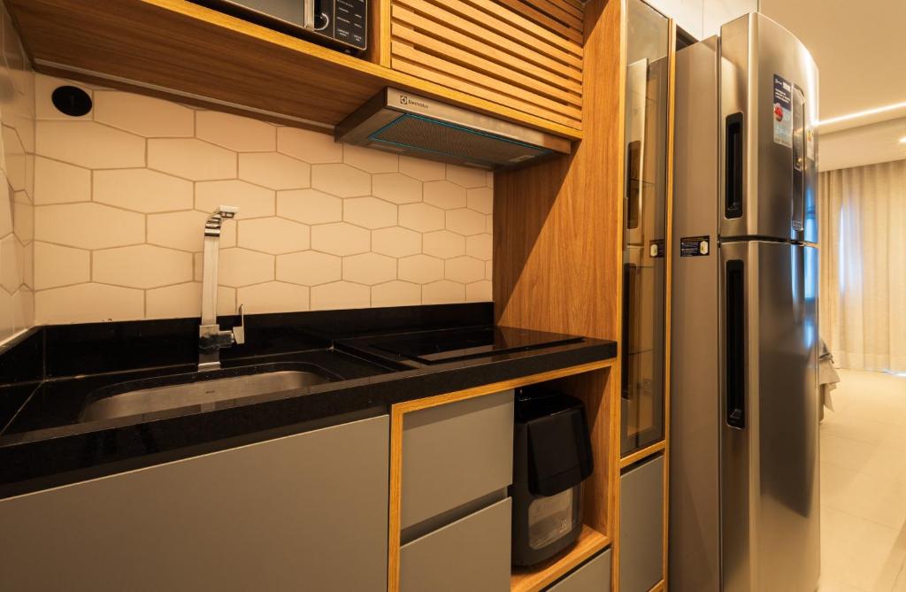 a kitchen with a sink and a stainless steel refrigerator at Art studio open space in Água Boa