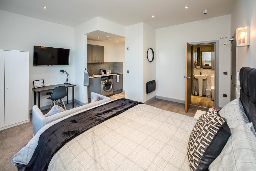 a bedroom with a bed and a desk and a kitchen at Edgerton Stays in Huddersfield