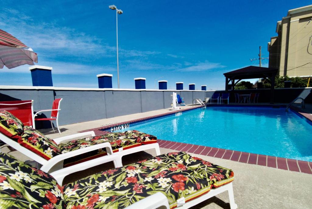 a swimming pool with two lounge chairs next to it at Days Inn & Suites by Wyndham Thibodaux in Thibodaux