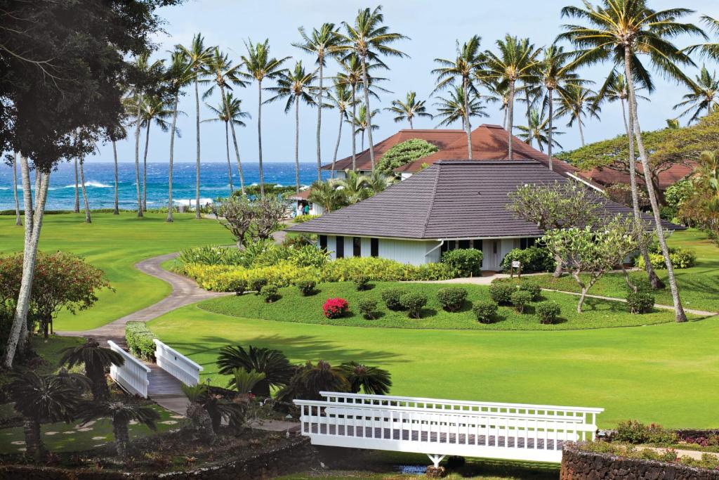 a house on a golf course with palm trees and the ocean at Kiahuna Plantation Resort Kauai by OUTRIGGER in Koloa