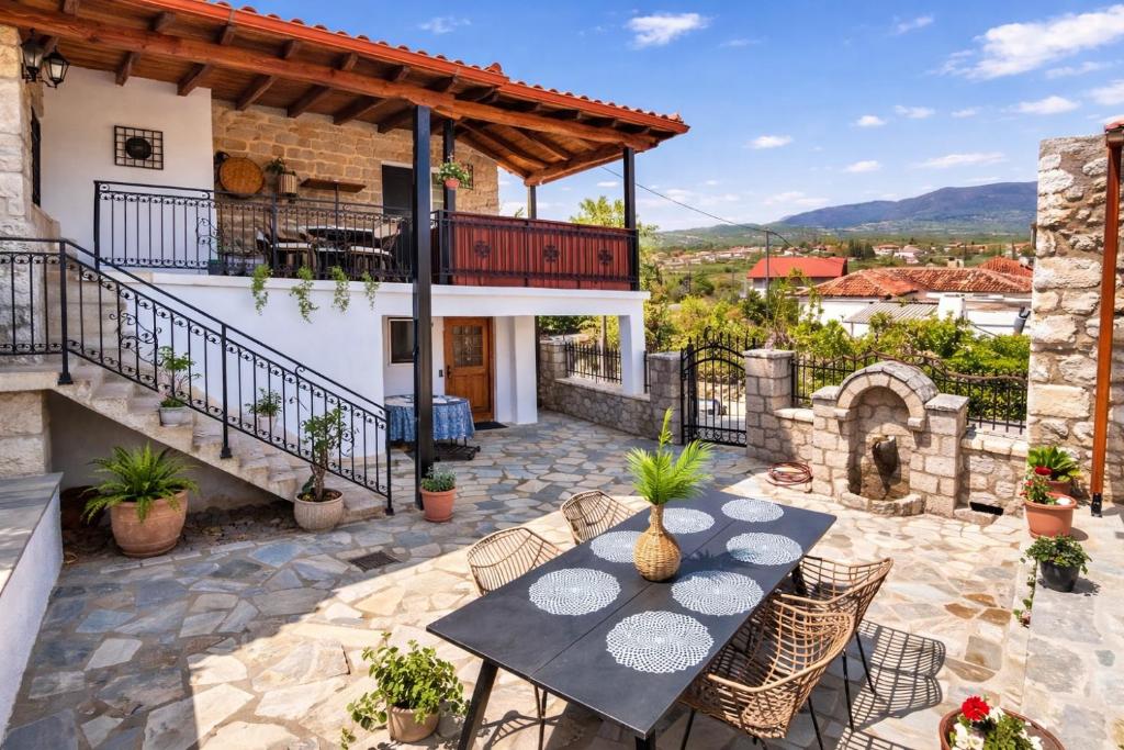 a patio with a table and chairs and a building at Archontiko Kastellia - Stone Guesthouse with Fireplace and Mountain View in Evangelístria