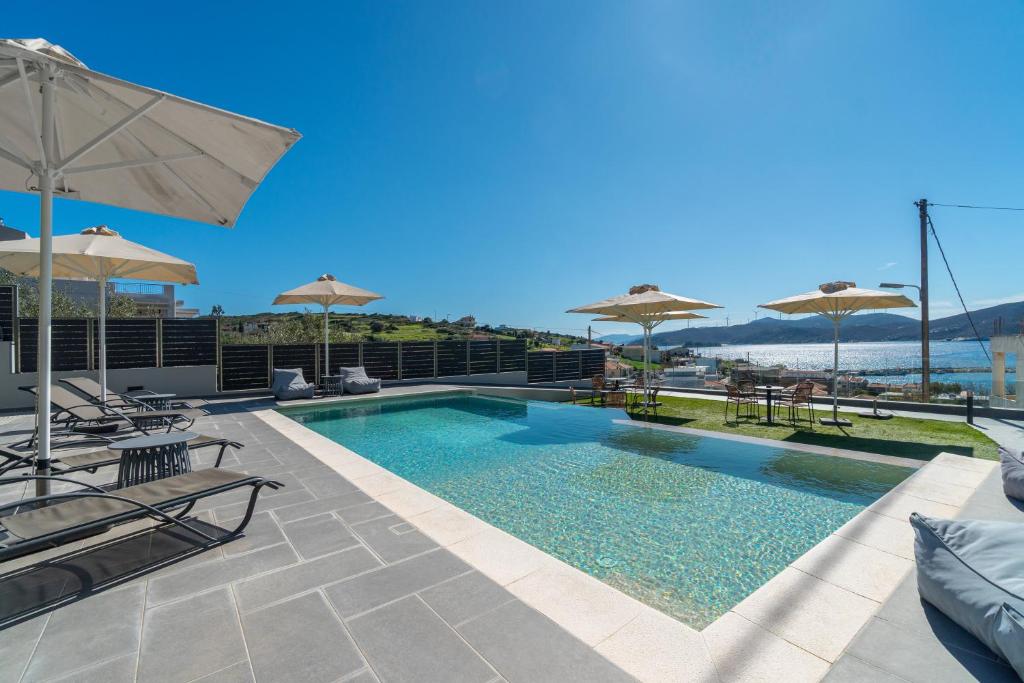 a swimming pool with chairs and umbrellas on a building at Harmony Apartments in Agioi Apostoli