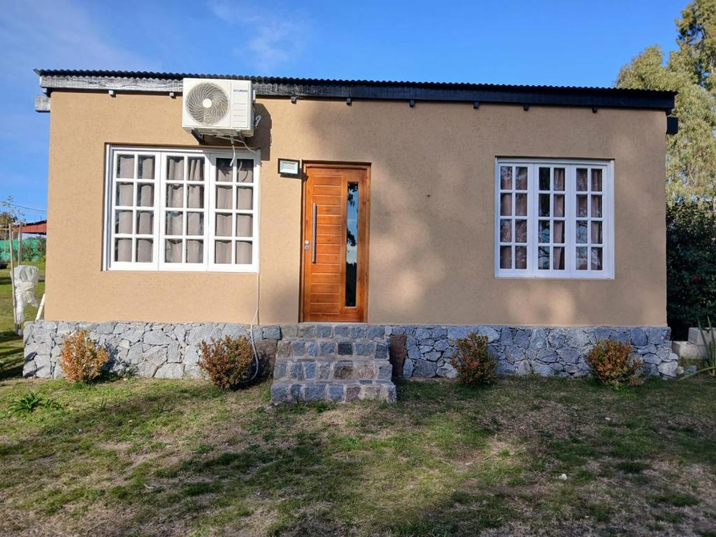 a small house with a door and a stone wall at Cabaña la Monita in Tandil