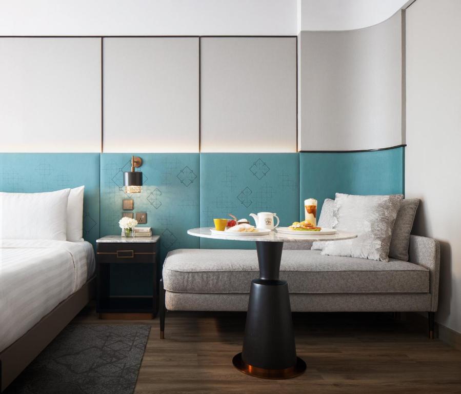 A close view of the bed edge and a gray sofa arranged around a small table set with breakfast.