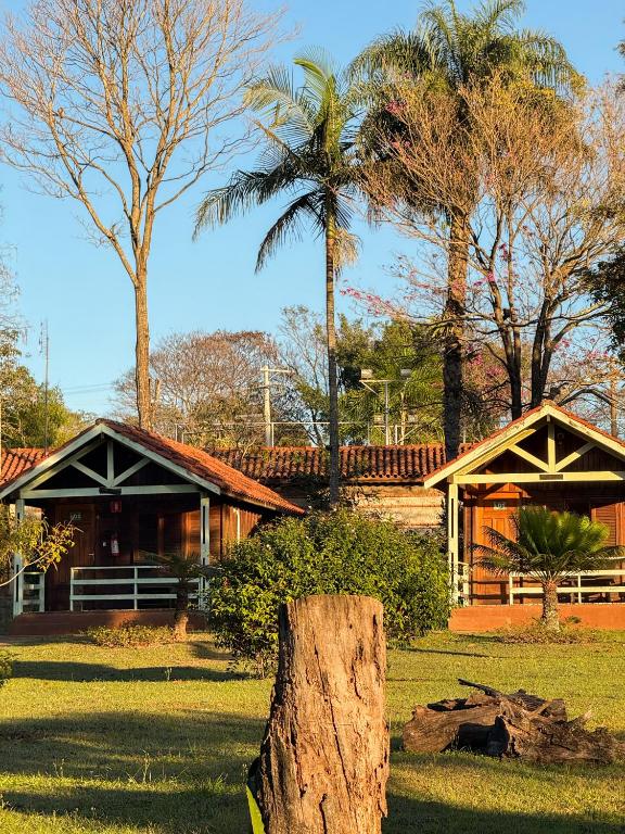 a log in the grass in front of a house at Pousada Sabiá in Brotas