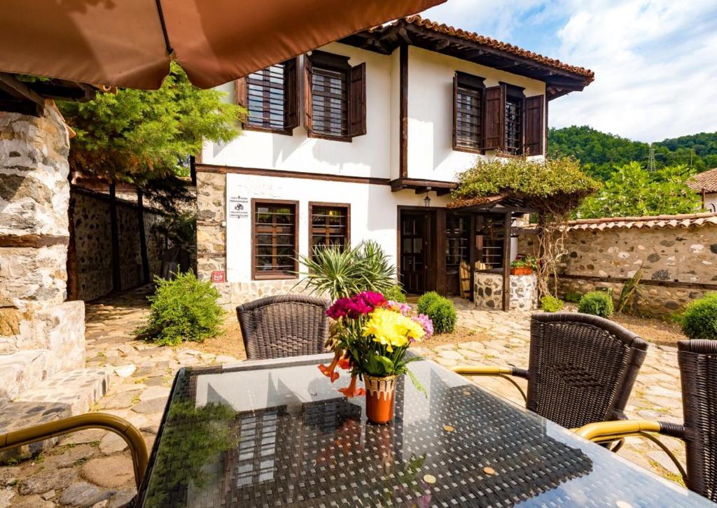 a patio with a table with flowers on it at Къща за гости Старият Град Златоград in Zlatograd