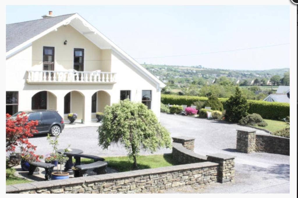 a white house with a car parked in the driveway at Sea Breeze B&B in Clonakilty