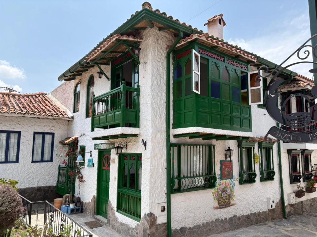 ein Gebäude mit grünen und weißen Türen und Fenstern in der Unterkunft Hostal La Cestería Pueblito Boyacense in Duitama