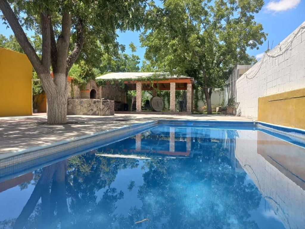 a swimming pool with a tree in front of a house at Quinta el molino in Parras de la Fuente