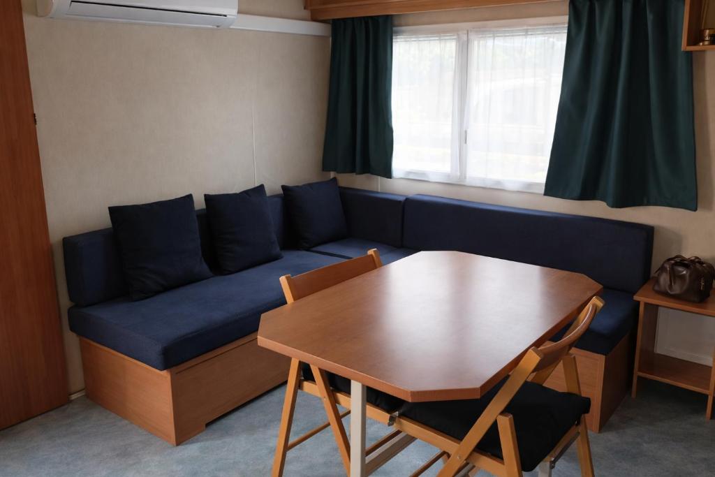 a living room with a blue couch and a table at Mobil-home tout équipé Le Castellet les pins doux 2 in Le Castellet
