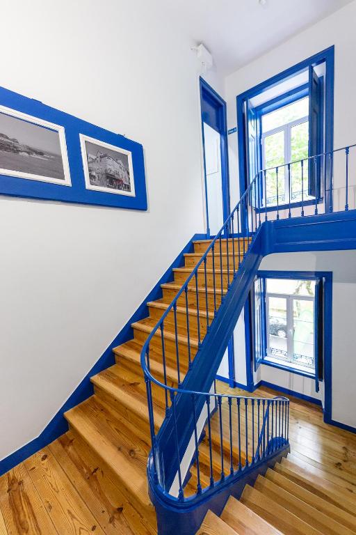 a blue staircase in a room with wooden floors at Help Yourself Hostels - Parede in Parede
