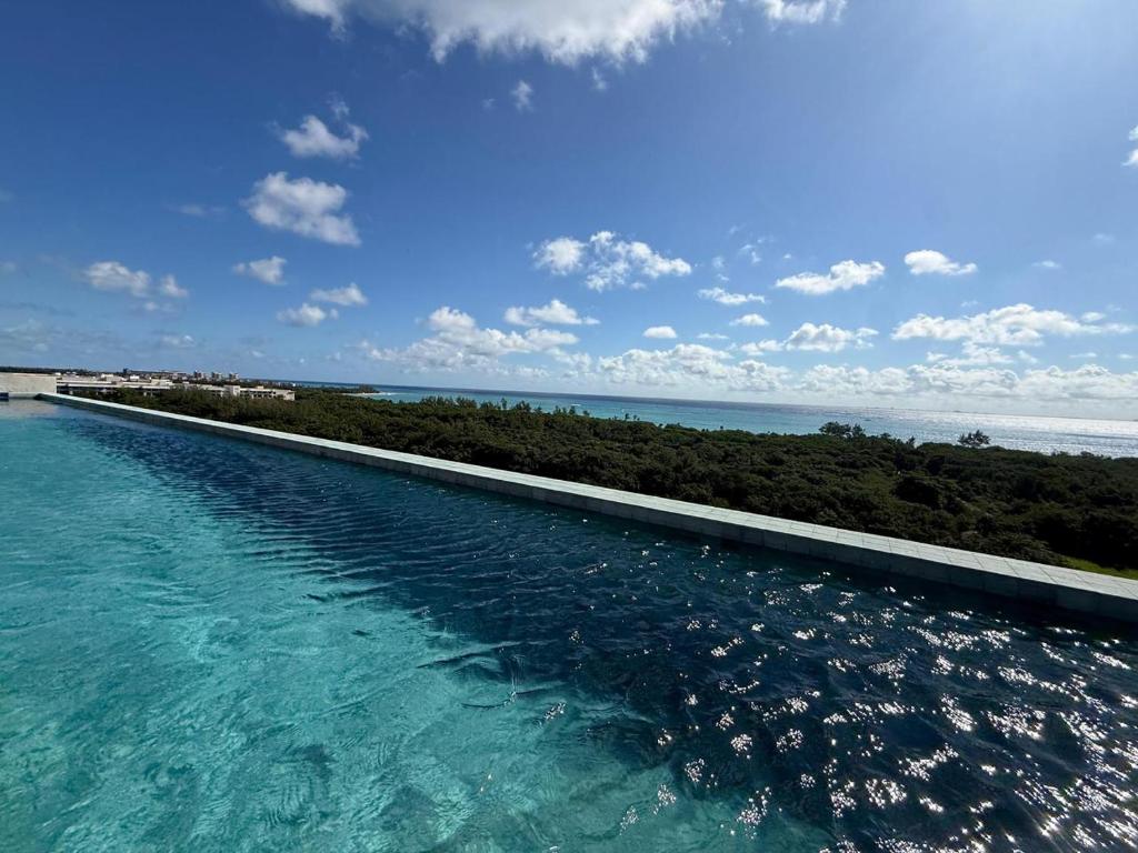 a swimming pool with the ocean in the background at Beach Studio Playa del Carmen MX in Playa del Carmen