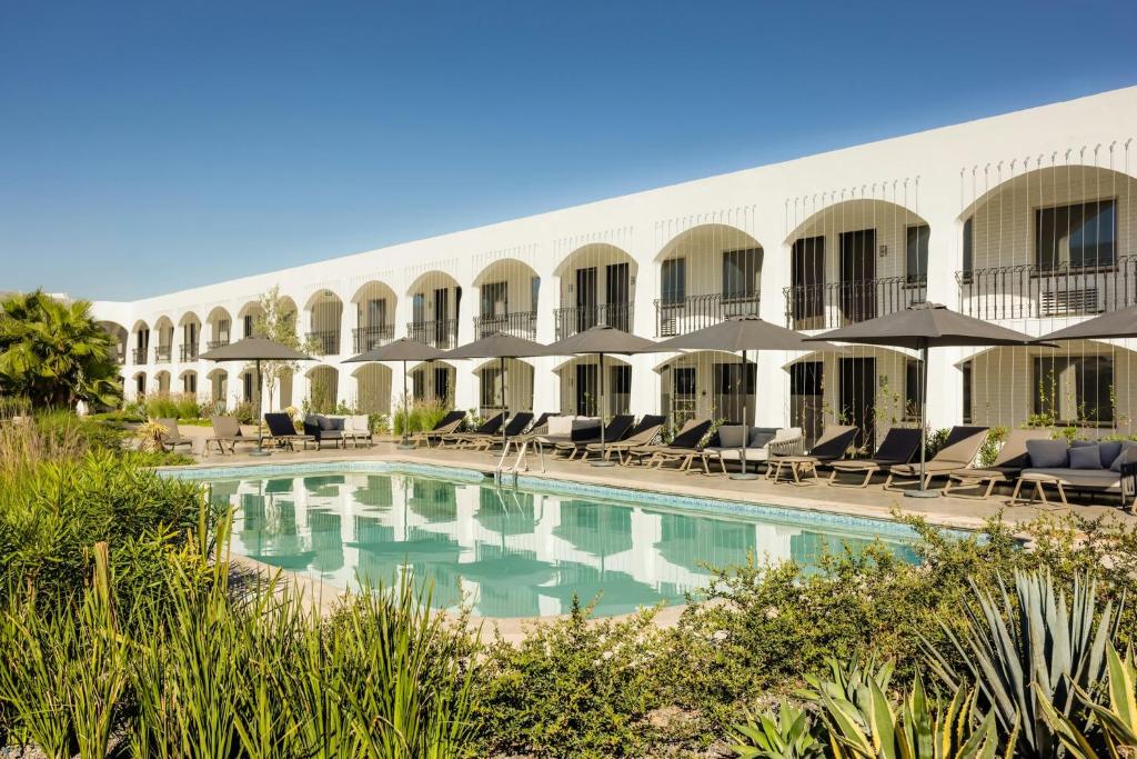a hotel with a pool and chairs and umbrellas at Gamma Ciudad Juarez in Ciudad Juárez