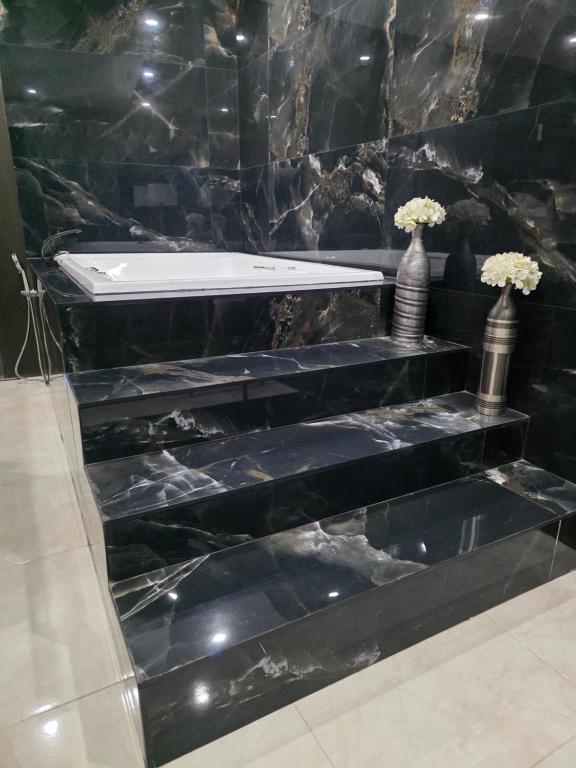 ein Badezimmer mit schwarzer Marmortreppe und Vasen mit Blumen in der Unterkunft Cataleya red in La Coyotera