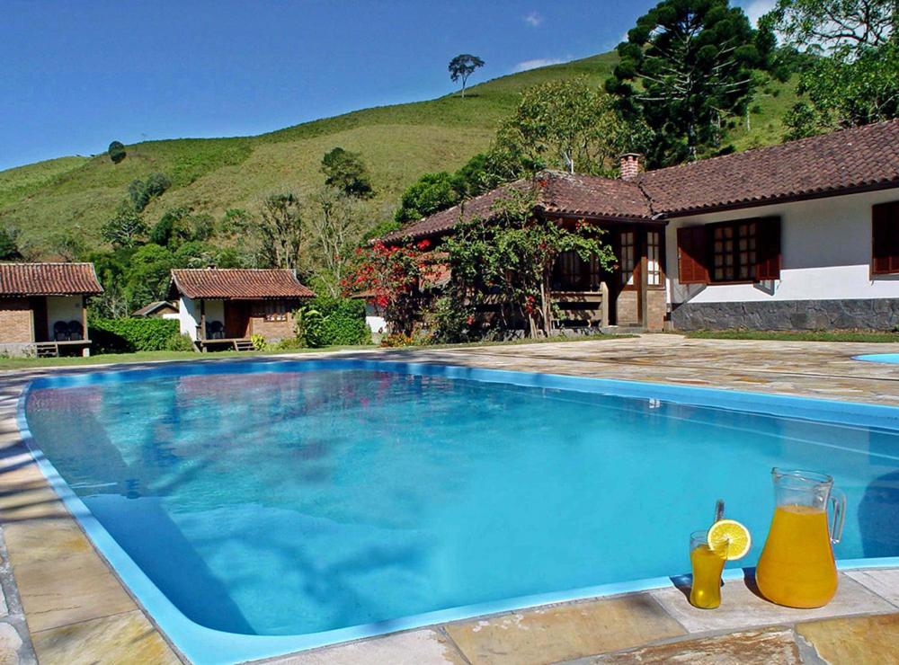 una gran piscina azul frente a una casa en Pousada do Encanto, en Visconde De Maua