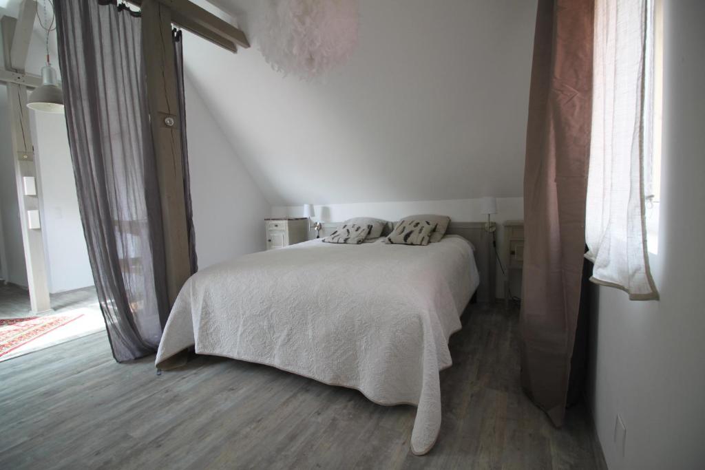 a bedroom with a white bed with two pillows on it at L'Atelier des dépendances in Lipsheim