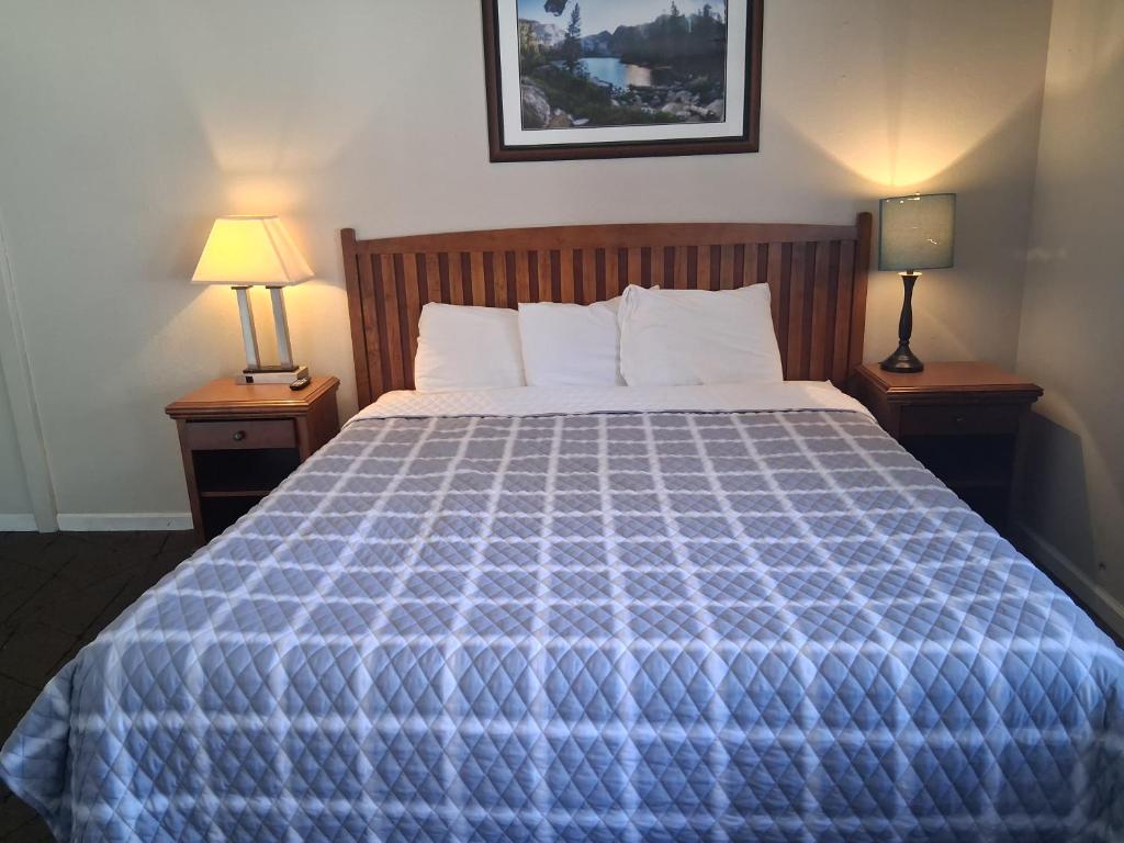 a bedroom with a bed with a blue comforter and two lamps at A&A Lake Tahoe Inn in South Lake Tahoe
