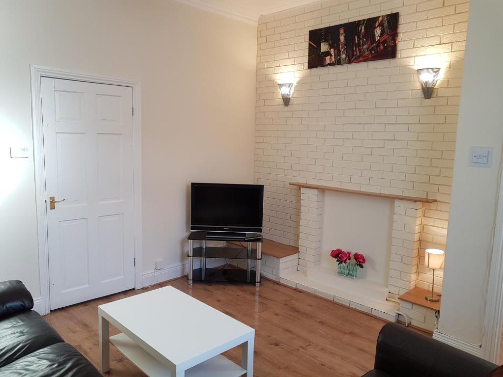 uma sala de estar com uma televisão e uma parede de tijolos em Sea Glass Cottage em Sunderland