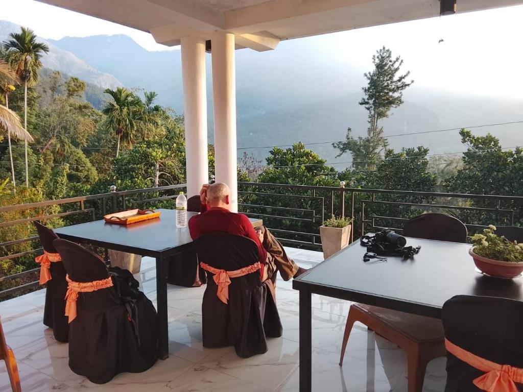 a man sitting at two tables on a patio at Devil mountain guest in Kalupahana