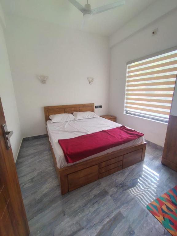 a bedroom with a large bed with a red blanket at Poozhikuth Homestay in Sultan Bathery