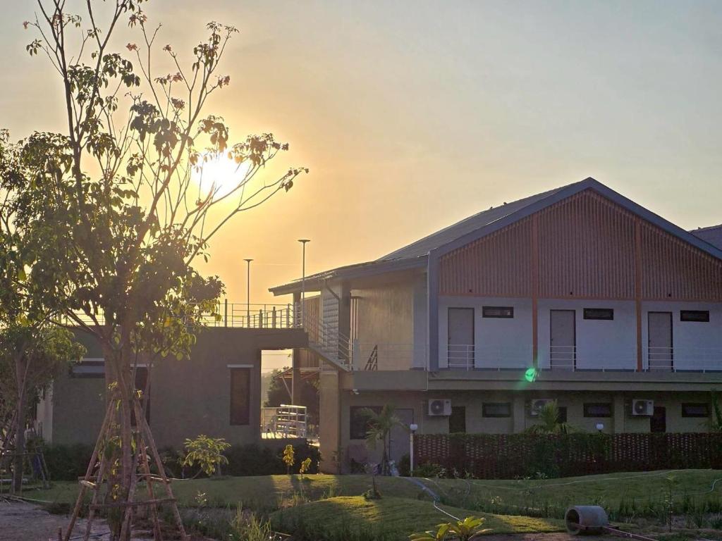 a house with the sun setting behind it at The Y Habitat in Kanchanaburi City