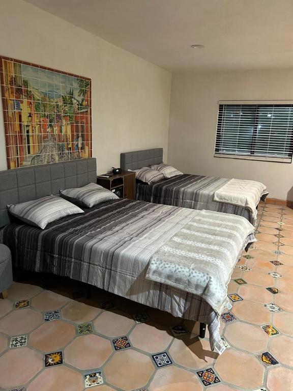 a bedroom with two beds and a painting on the wall at AG Dusty Luxe Suite #3 in San Miguel de Allende