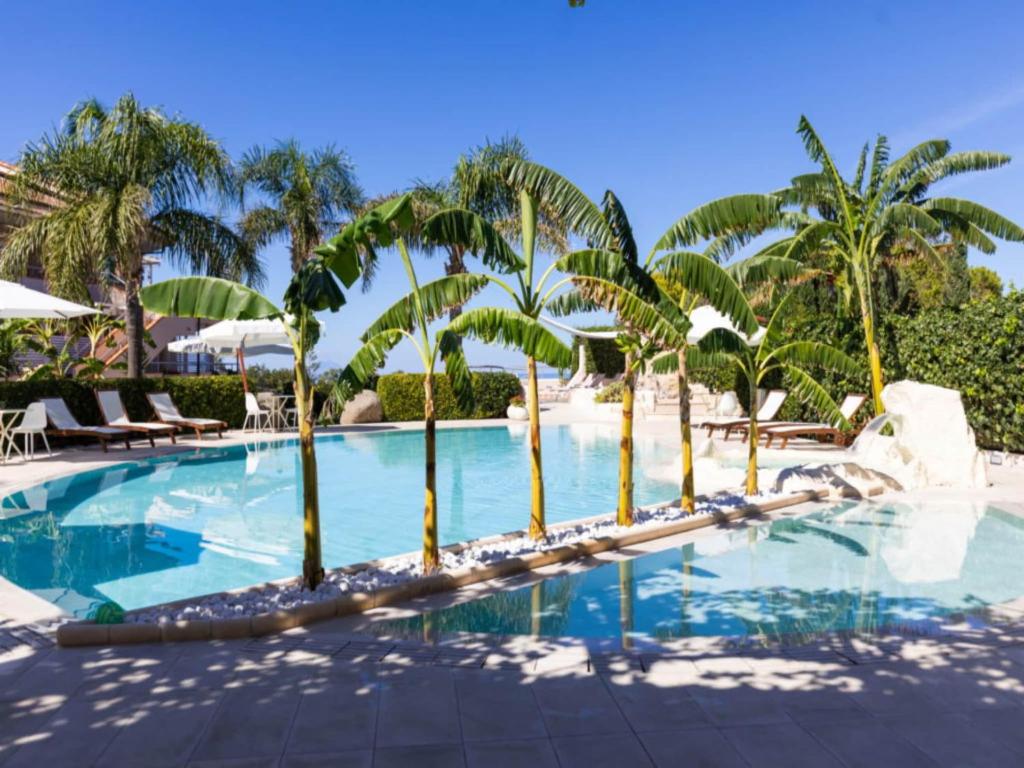 a pool at the resort with palm trees at Studio for couples in Capo Vaticano with pool in Capo Vaticano