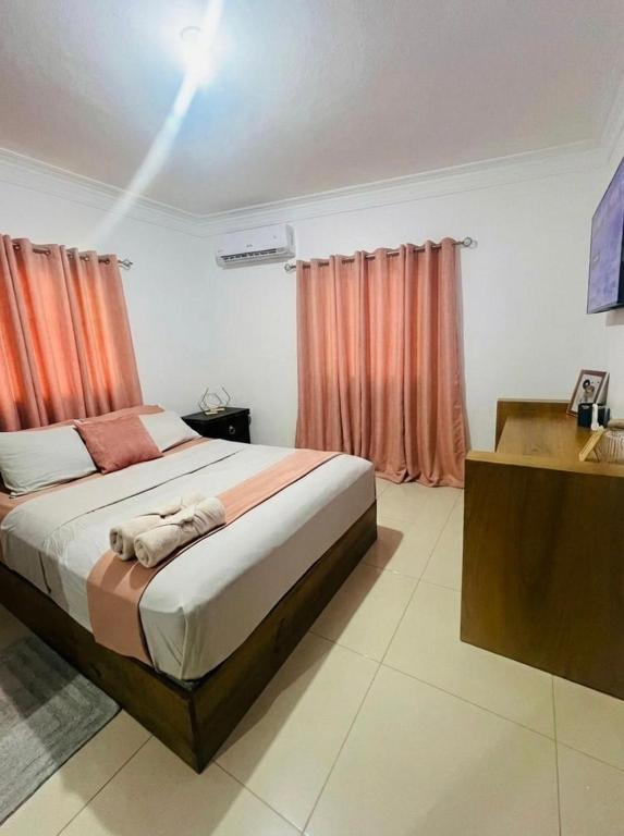 a bedroom with a large bed with orange curtains at Brisas de las Montañas in Jarabacoa