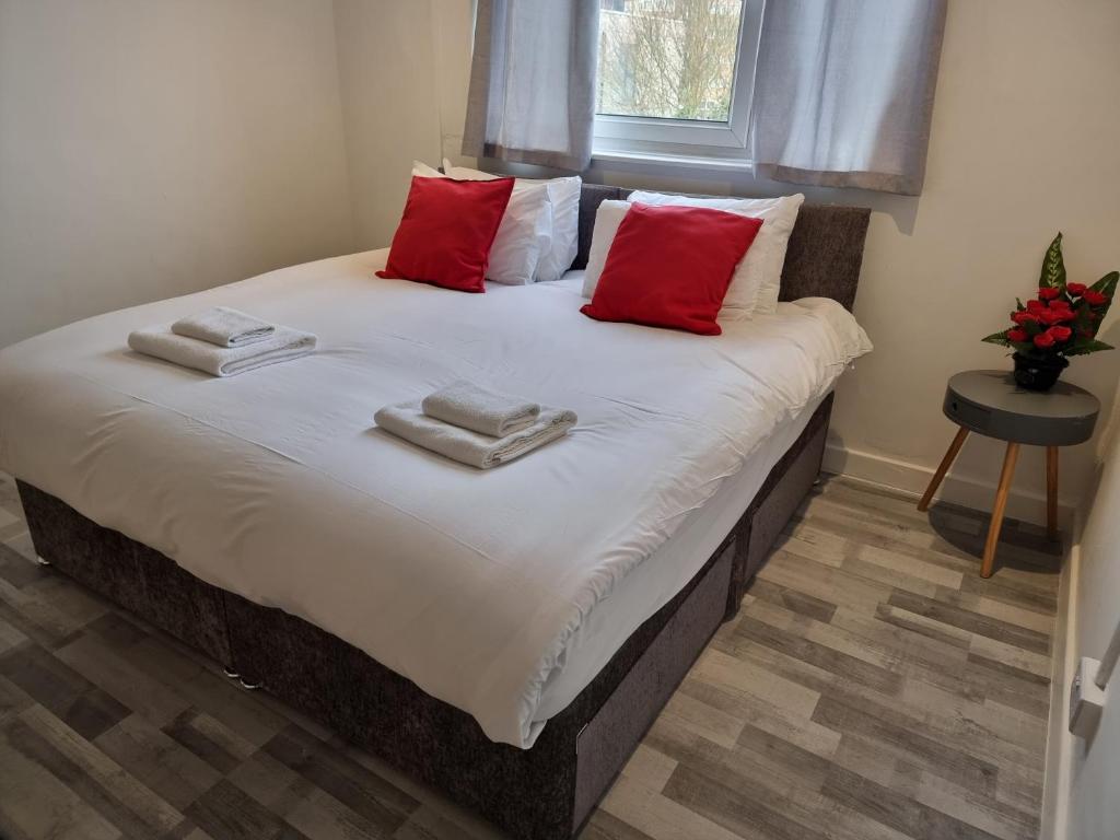 a bed with red pillows and towels on it at Away Home in London