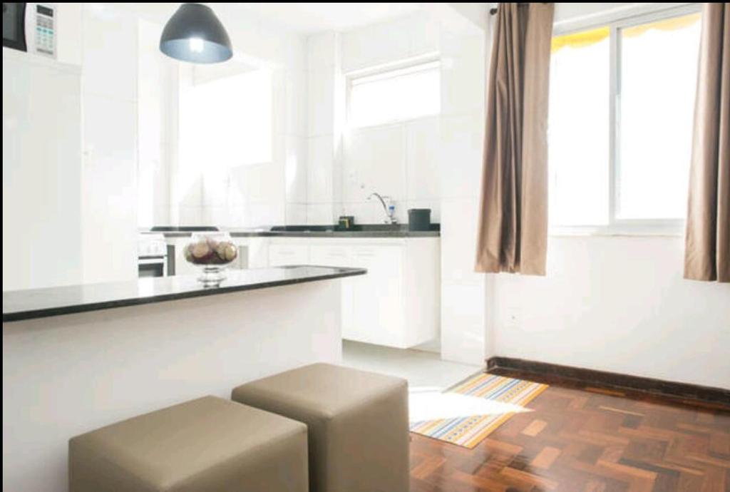 una cocina blanca con taburete y barra en Lindo Apartamento a 500m da Barra, en Salvador