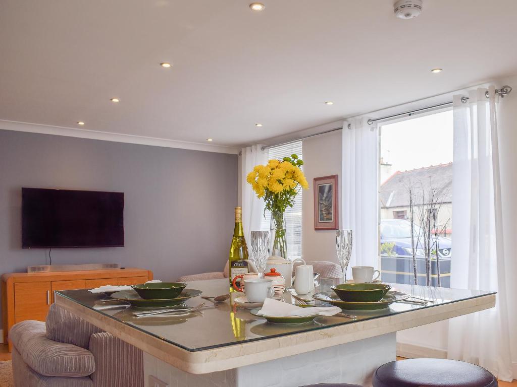 a living room with a table with dishes and flowers at Bramble Cottage in Leven