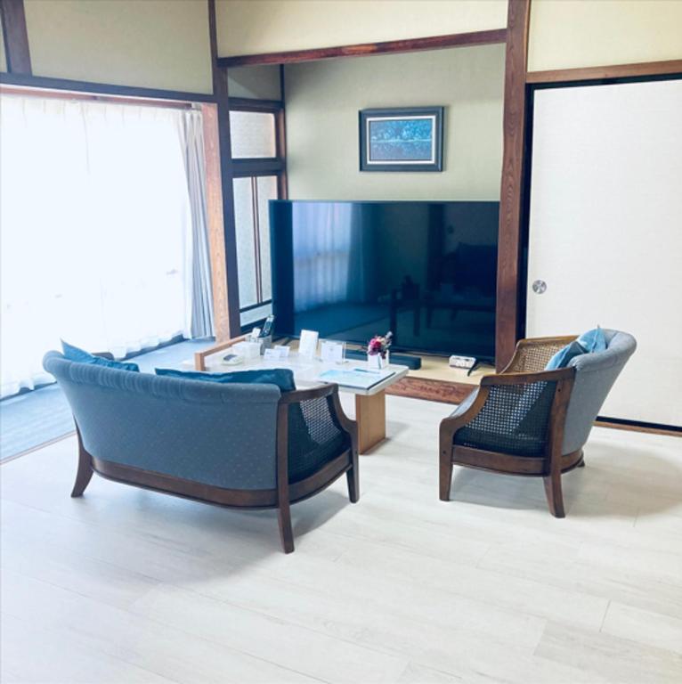 a living room with a couch and a table and chairs at 福のや in Unnan