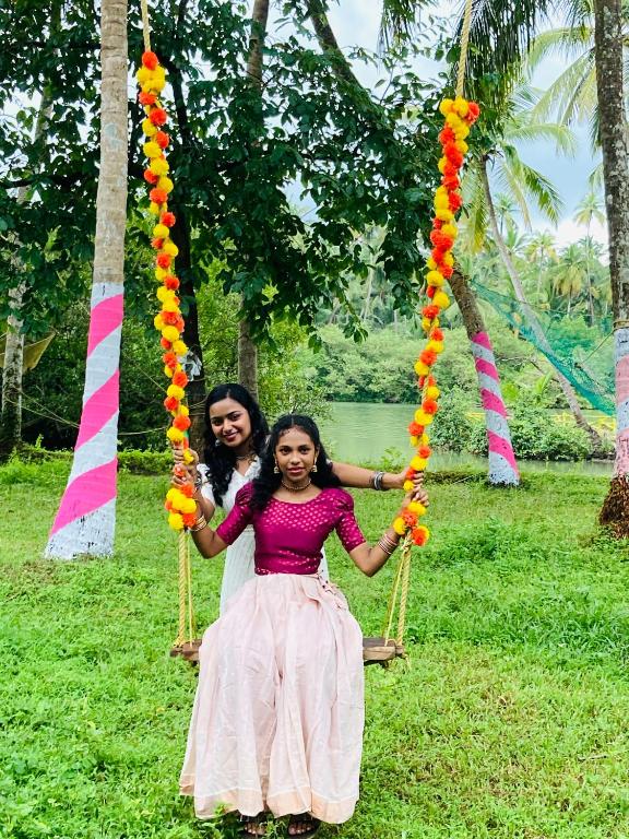 two girls are sitting on a swing at Kakkakuni heritage in Kozhikode