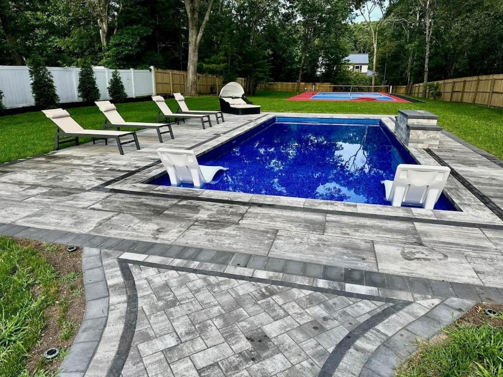 a swimming pool with two chairs and a table at Hamptons Tiana Bay Oasis in Hampton Bays