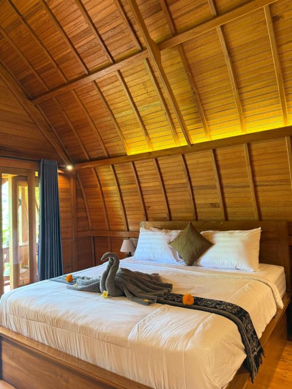 a large bed in a room with a wooden ceiling at Lumbung Intan in Sidemen