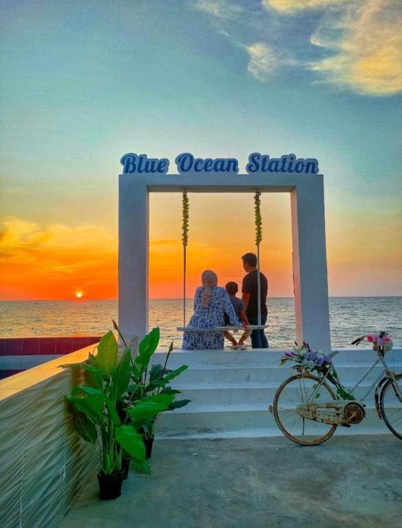 a couple sitting on a porch watching the sunset on the beach at 爱上海蓝蓝屋民宿 Blue Ocean Station in Penampang