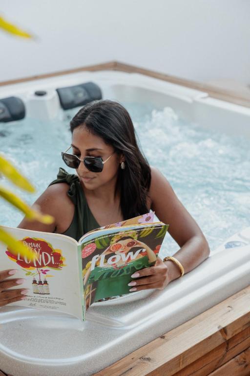 a woman reading a book in a swimming pool at Lodge des palmiers - jacuzzi in Salazie