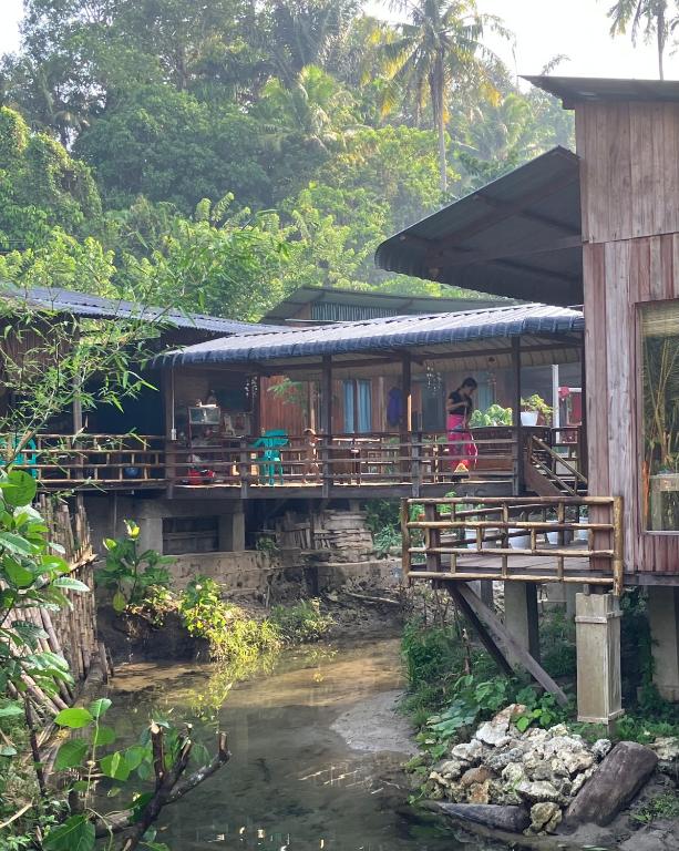 a house with a bridge next to a river at Cucu Suzanne in Lasikin