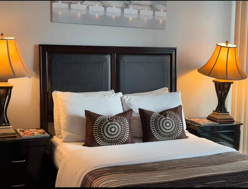 a bedroom with a bed with pillows and two lamps at Spacious-Cozy 2Bed Condo in Square Ones Misissauga in Mississauga