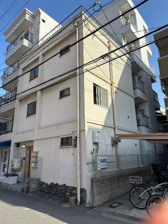 a white building with a bike parked in front of it at 寬居 kuanju 一棟貸し 広々一戸建て JR桜ノ宮駅徒歩3分 最大8名 梅田 大阪城公園アクセス良好 in Osaka